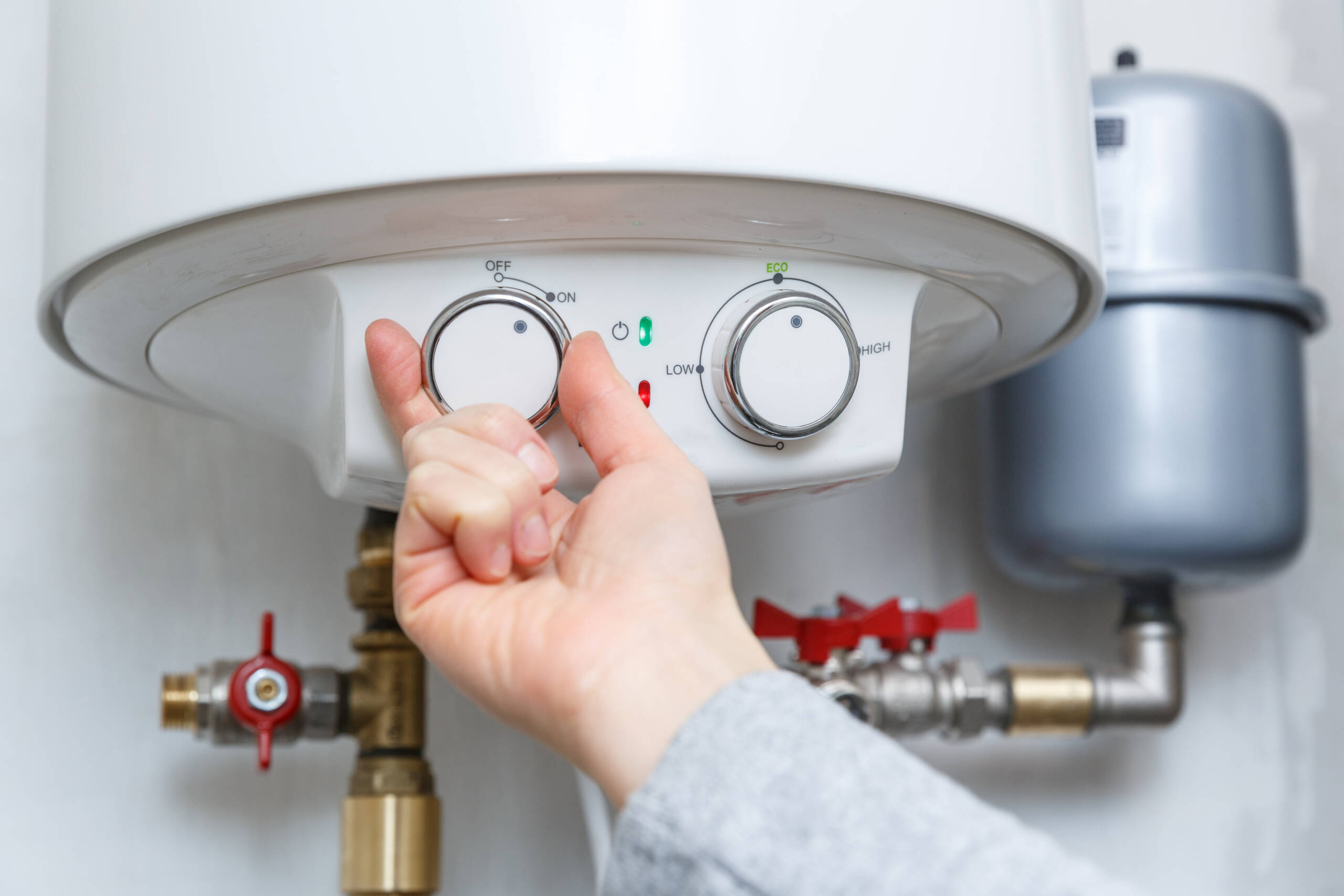 Female hand turning on electric water heater (boiler).